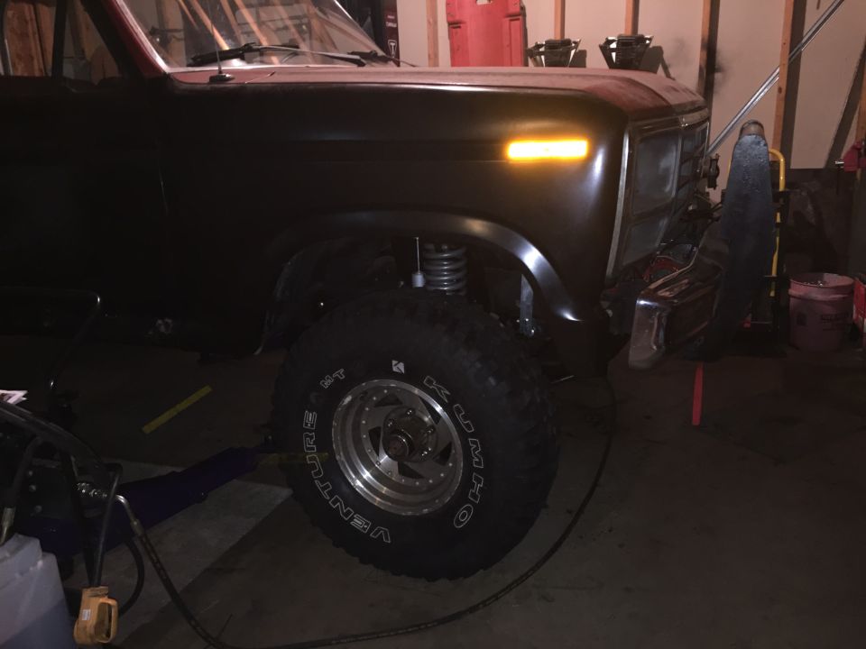 Front three-quarter view of a black lifted Ford Bronco in a dim garage