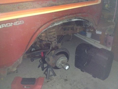 Front wheel well of a red Bronco with hub exposed and brake parts removed