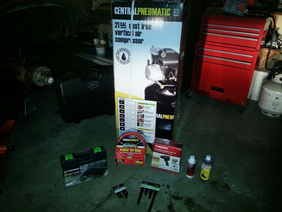 Central Pneumatic air compressor box and tools staged on a garage floor