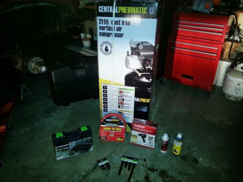 Central Pneumatic air compressor box with air hose and tools in a garage