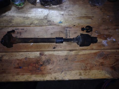 Drive shaft part on a wooden surface with "SUPERMOTORS.NET" visible