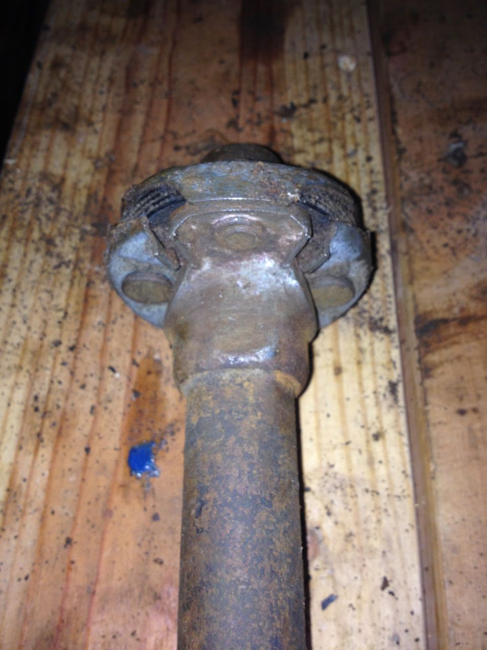 rusted metal shaft with a U-joint, resting on wood