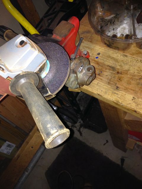 Angle grinder with a grinding wheel held by a red vise on a wooden workbench