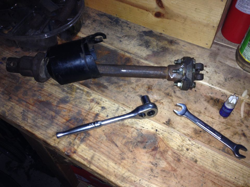 Photo of a driveshaft or axle shaft with flange and hand tools on a workbench