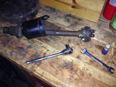 Photo of an axle shaft with bolted flange and tools on a workbench