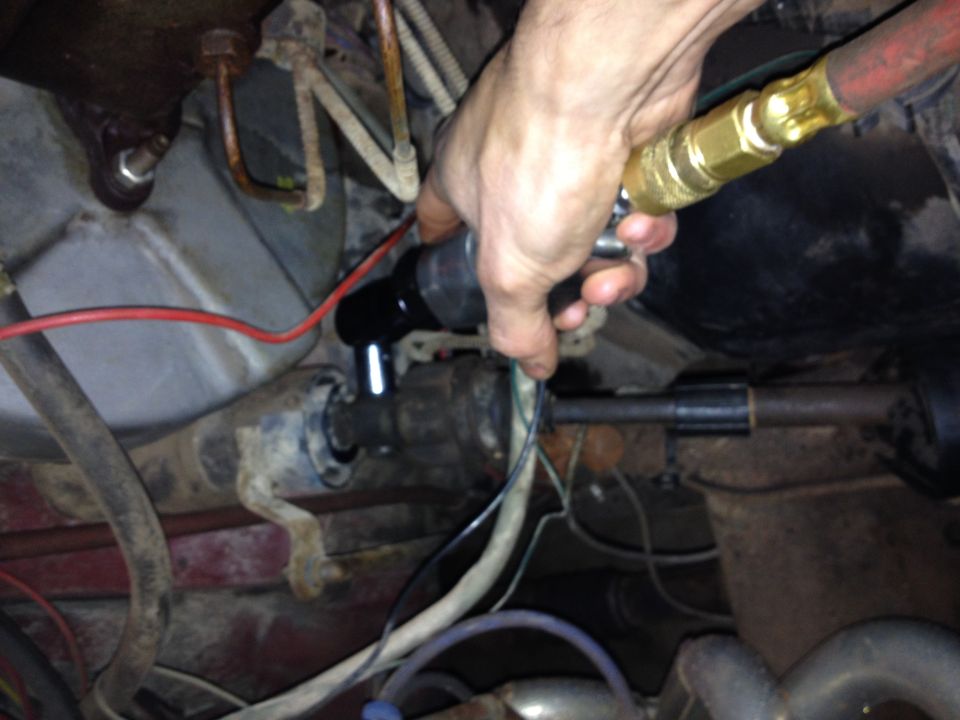 Photo of a hand using a tool on engine bay components and wiring