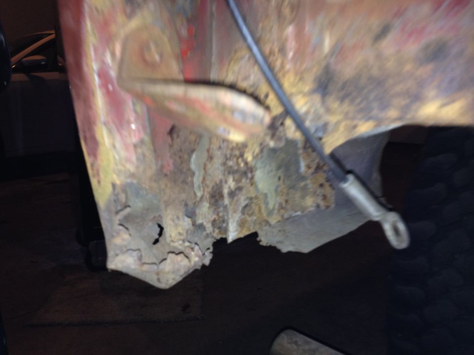 Photo of a rusted-through body panel corner with welding work