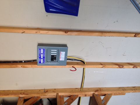 Photo of a small electrical breaker panel mounted on a garage wall