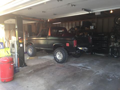 Photo of a black Bronco-style truck parked on a lift in a garage