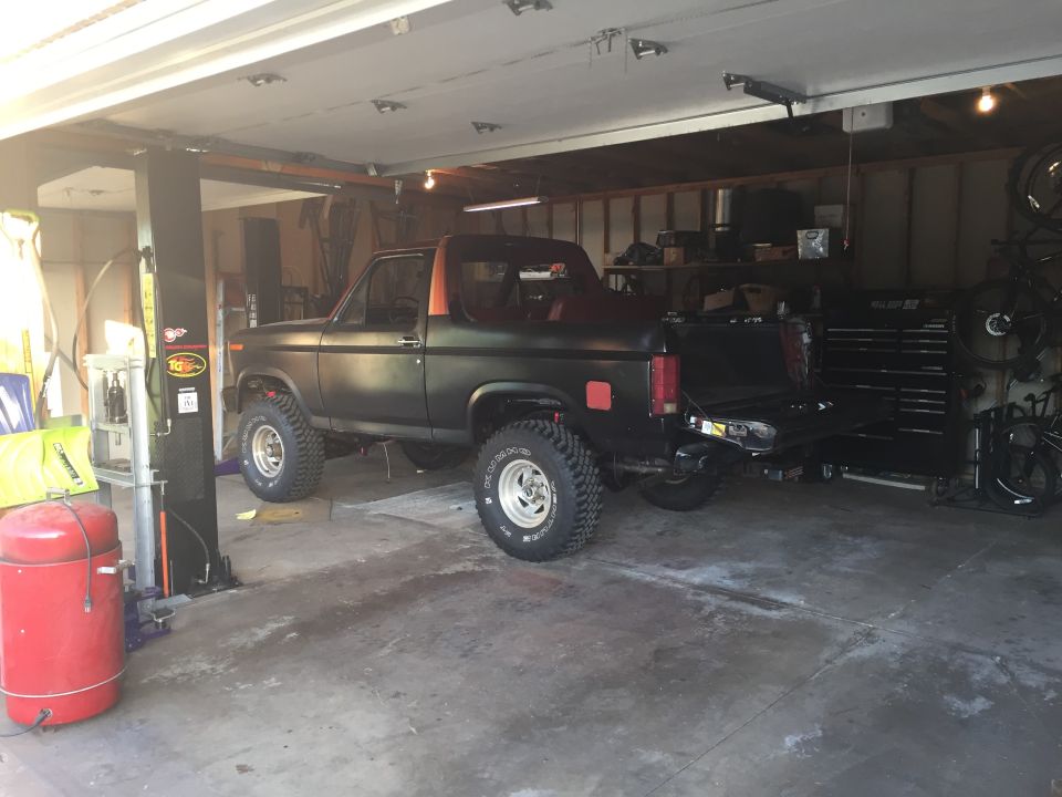 Photo of a black Bronco-style truck parked on a lift in a garage
