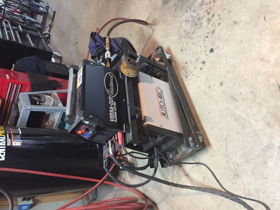 Photo of a plasma cutter and welding equipment on a garage floor