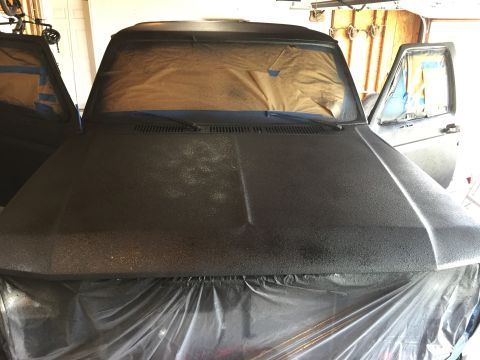 Project truck hood in fresh primer coating in a garage