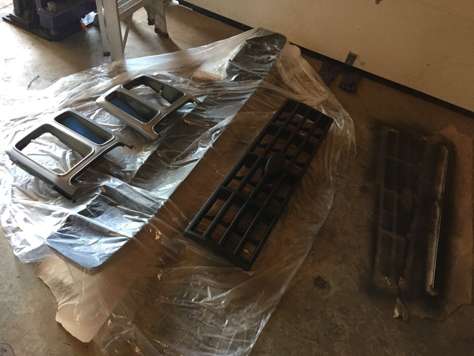 Truck grille and trim parts laid out on plastic for painting