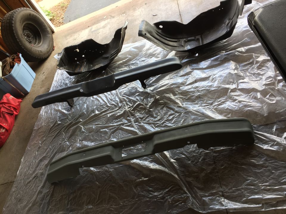 Painted truck bumper and inner fender parts on plastic sheeting