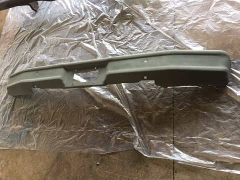 Freshly painted truck front bumper on plastic sheeting