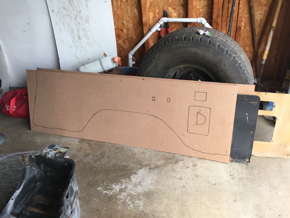 Hand-drawn cardboard template for a truck body panel in a garage