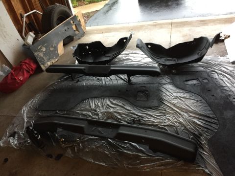 Painted truck bumper and inner fender parts on plastic in a garage