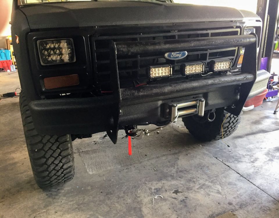 Black Ford truck grille and front bumper with winch and LED lights