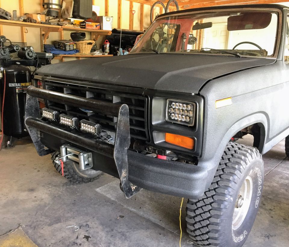 Gray Ford truck front three-quarter view with grille guard in a garage