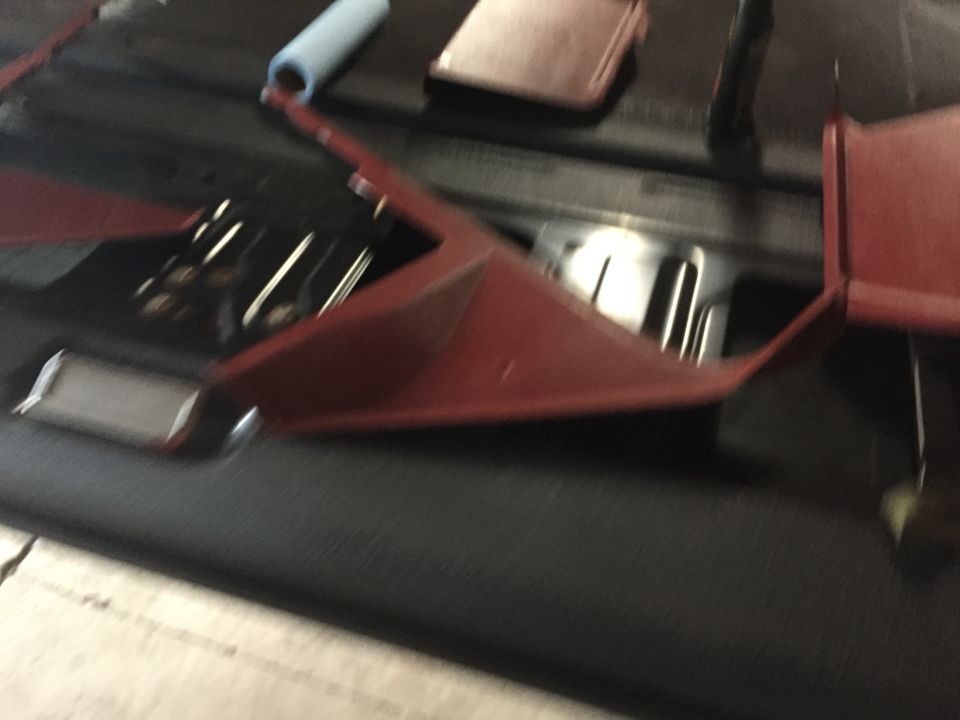 Blurry close-up of red metal brackets on a vehicle floor pan