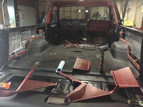 Bare interior of a Ford truck with floor pan and red brackets