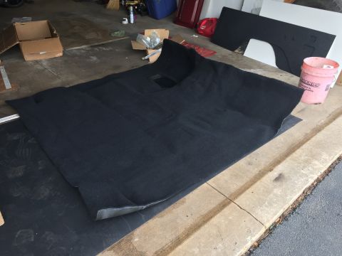 Black molded automotive carpet laid out on a garage floor
