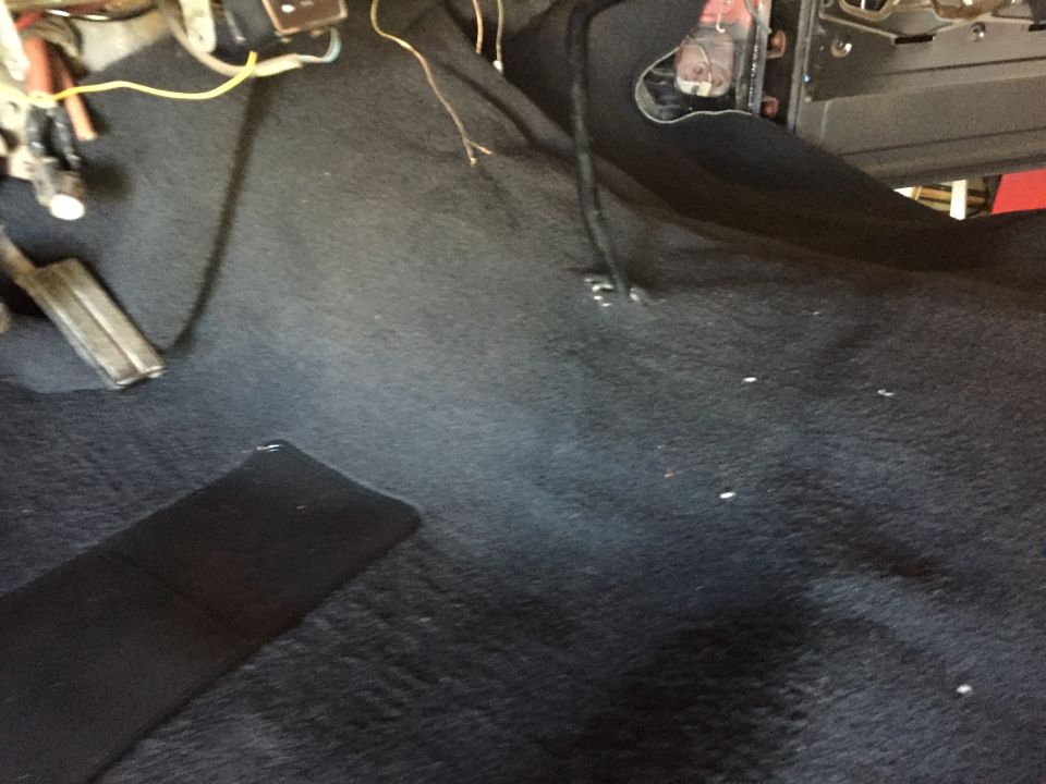 Black carpet floor in a vehicle interior near the dash wiring