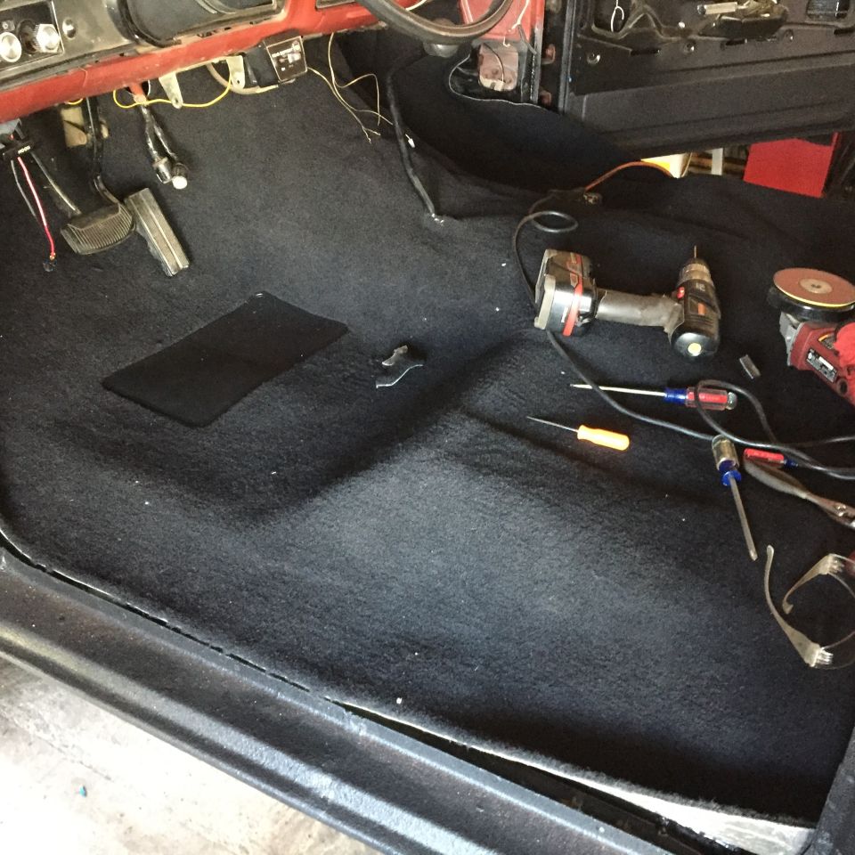 Black carpet in a Ford truck interior with tools and pedals