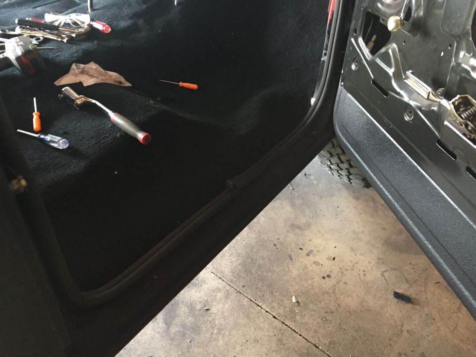 Black carpet and open door sill of a Ford truck with tools