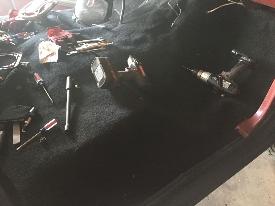 Black carpet on a vehicle floor covered with hand and power tools