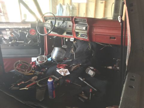 Ford truck interior with red dash, carpet, and scattered tools