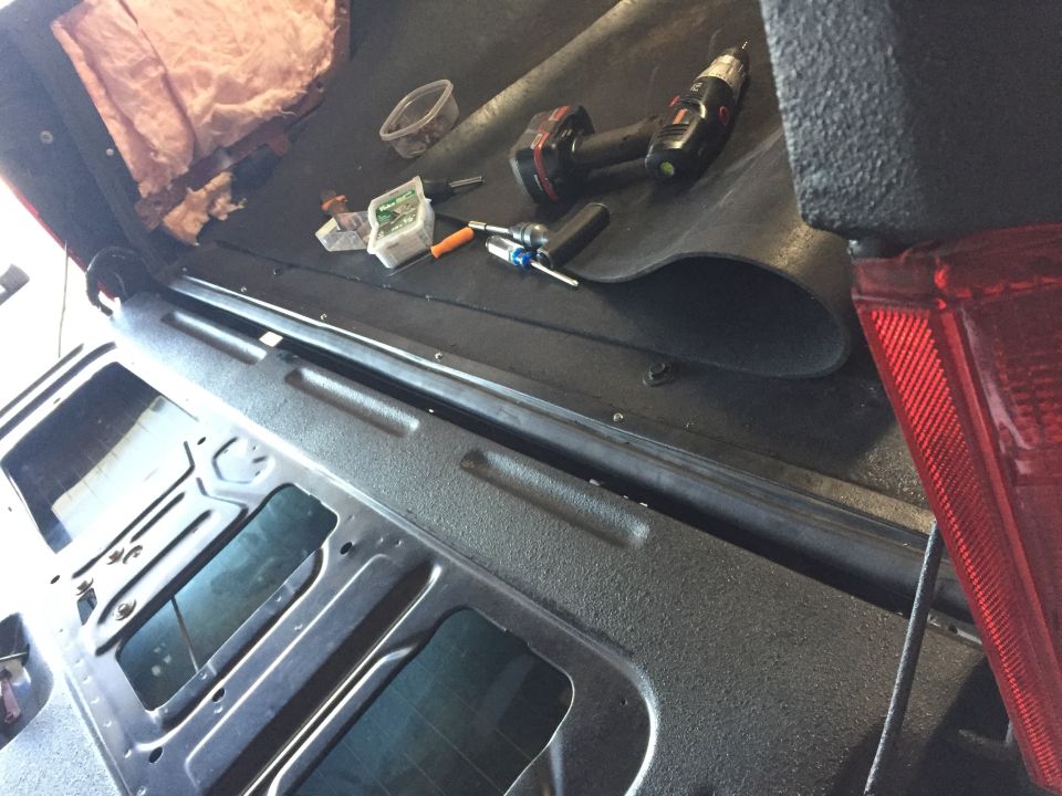 Black interior quarter panel and rear floor of a Ford truck with tools
