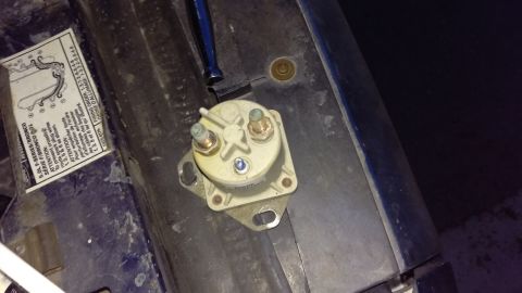 1994 Ford Bronco - Photograph of a starter solenoid mounted on the fender next to an underhood warning label.