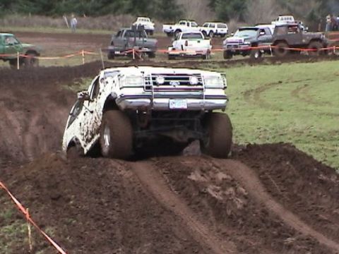 1989 Ford Bronco - A white 1989 Ford Bronco navigates a challenging muddy terrain during an off-road event.