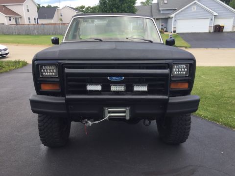 Black 1980s Ford Bronco front view with LED headlights and winch
