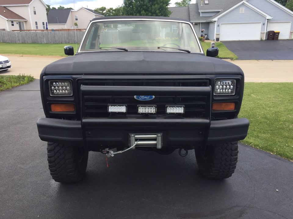 Black 1980s Ford Bronco front view with LED headlights and winch