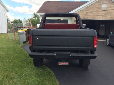 Rear view of a black Ford Bronco with a red interior bench seat.