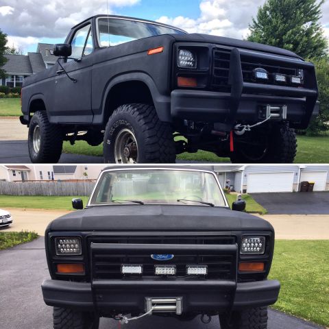 Matte black lifted 1980s Ford pickup truck with bull bar, winch, and LED lights.
