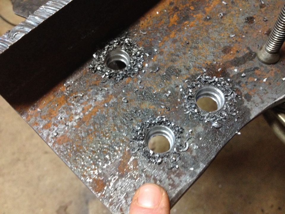 Metal plate with three threaded holes and metal shavings.