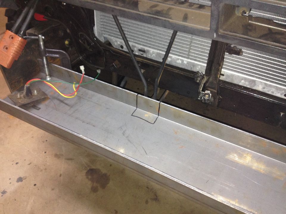 Custom metal bumper fabrication with wiring and orange connector on a vehicle.