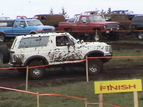 1989 Ford Bronco - Multiple trucks and SUVs participate in a mud bog event, with one white Bronco crossing the finish line.