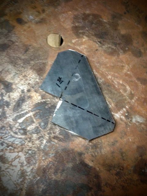 Cut sheet-metal bracket with dashed fold lines on a steel workbench