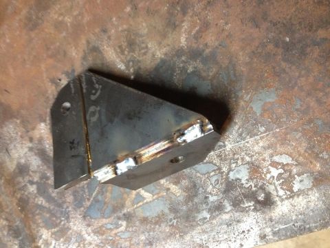 Welded sheet-metal gusset bracket with weld beads on a steel surface