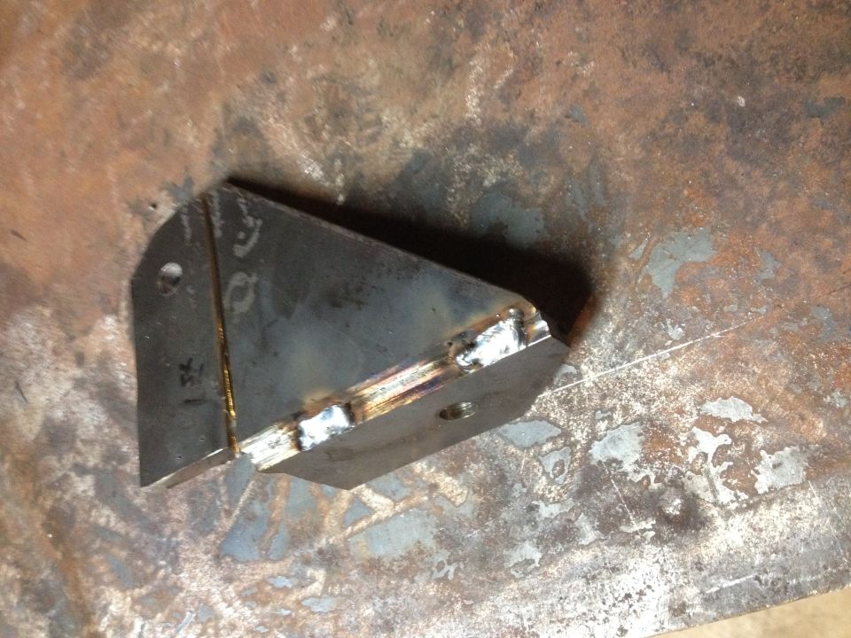 Welded sheet-metal gusset bracket with weld beads on a steel surface