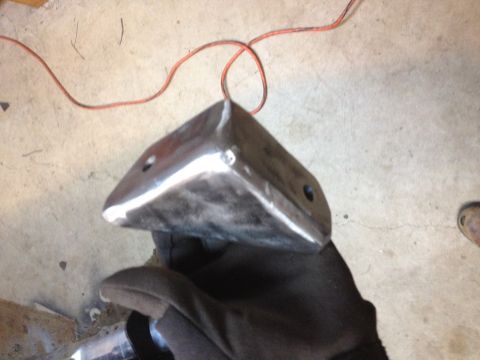 Gloved hand holding a folded and welded sheet-metal box bracket