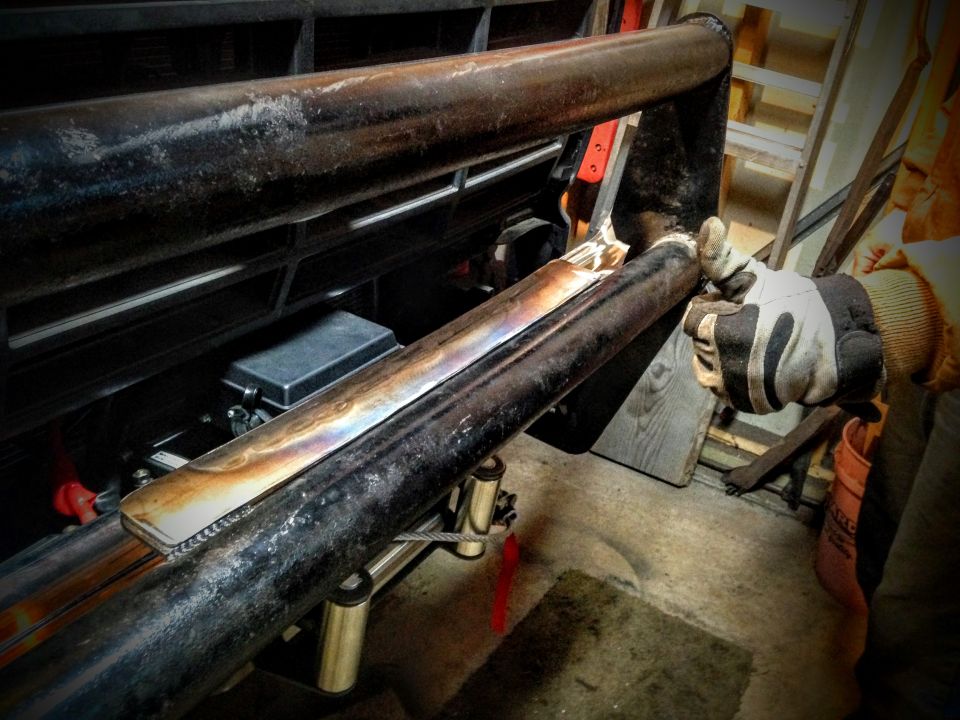 Gloved hand fitting a welded tubular bumper bar to a vehicle front end