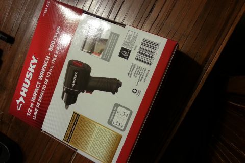 Husky 1/2 inch impact wrench retail box sitting on a wood table