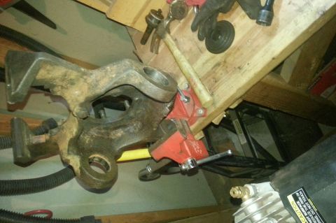 Steering knuckle clamped in a vise on a workbench
