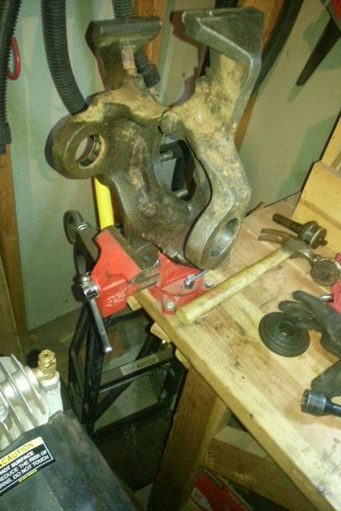 Steering knuckle clamped in a vise on a workbench