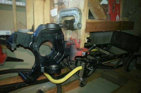 Black painted steering knuckle on a workbench next to a cart and tools